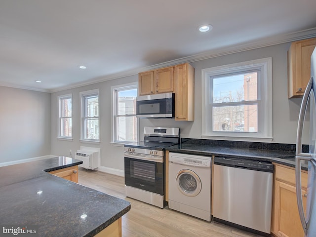 kitchen with washer / dryer, stainless steel appliances, dark stone countertops, light hardwood / wood-style floors, and ornamental molding