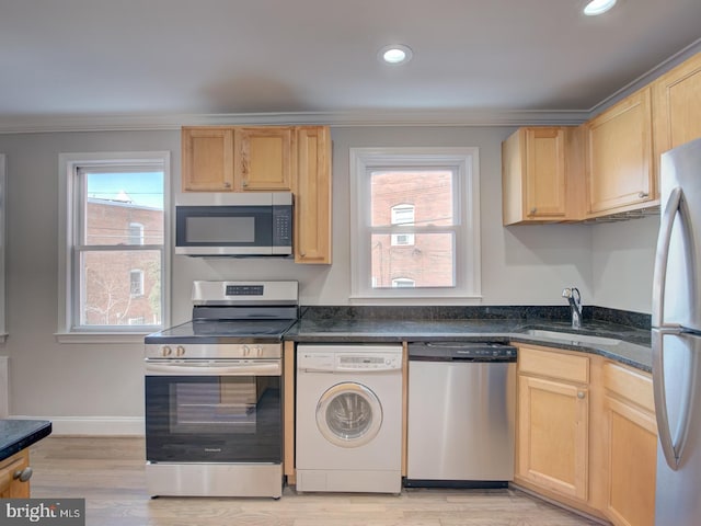 kitchen with light brown cabinets, washer / dryer, sink, appliances with stainless steel finishes, and light wood-type flooring