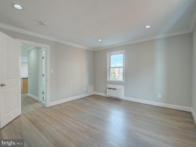 unfurnished room featuring a wall mounted air conditioner, light hardwood / wood-style flooring, and crown molding