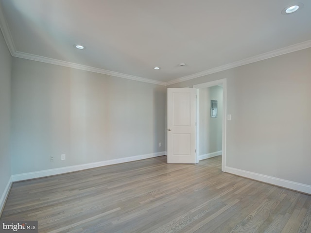 empty room featuring light hardwood / wood-style floors, electric panel, and crown molding