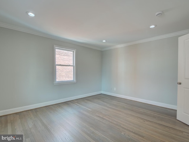 spare room featuring light wood-type flooring and crown molding