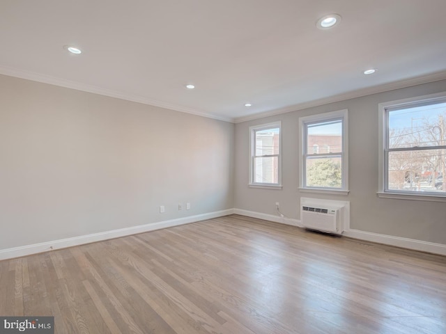 spare room with crown molding, light hardwood / wood-style floors, and a wall mounted AC