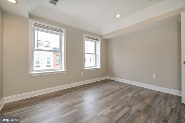 unfurnished room with baseboards, visible vents, and dark wood-style flooring
