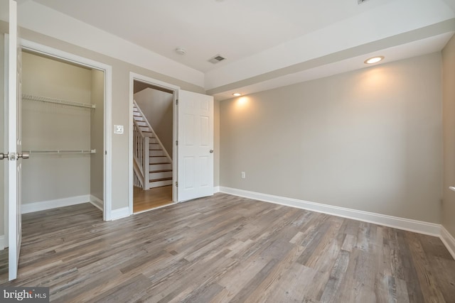 unfurnished bedroom with a walk in closet, hardwood / wood-style flooring, and a closet