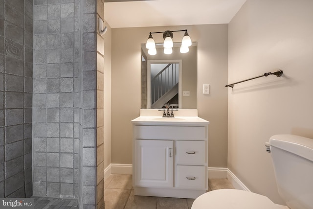 full bath with toilet, tiled shower, vanity, and baseboards