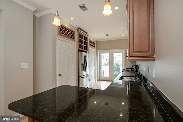 kitchen featuring decorative light fixtures, ornamental molding, dark stone countertops, stainless steel refrigerator with ice dispenser, and sink