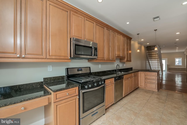 kitchen with dark stone counters, light tile patterned flooring, sink, pendant lighting, and stainless steel appliances