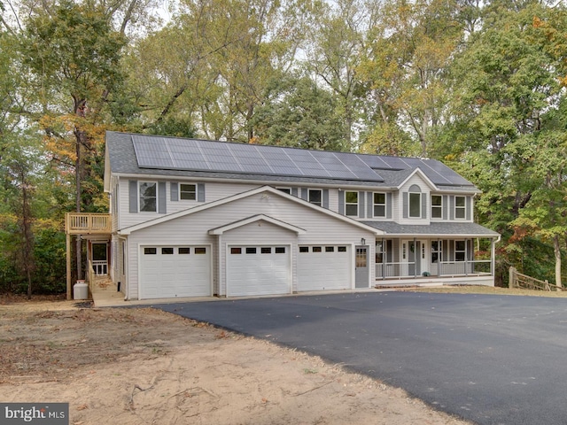 view of front facade featuring a porch, a garage, and solar panels