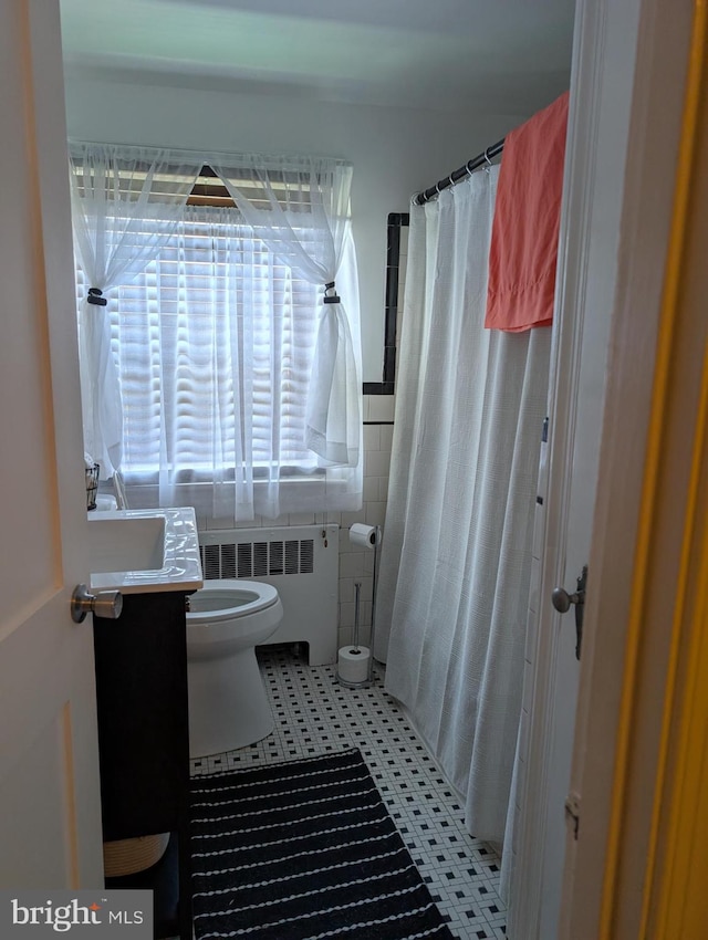 bathroom featuring vanity, a shower with curtain, radiator heating unit, and toilet