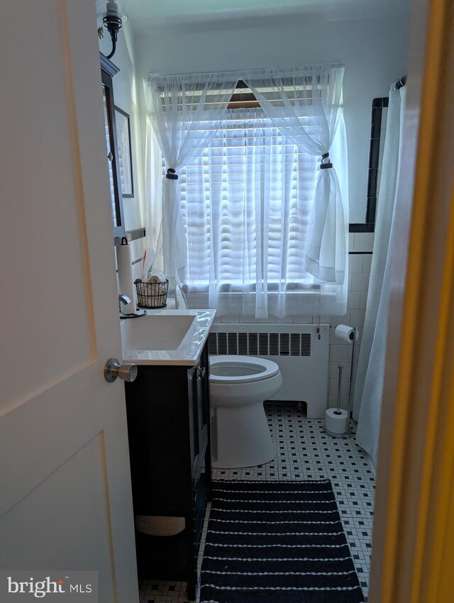 bathroom featuring toilet, radiator heating unit, vanity, and tile patterned floors