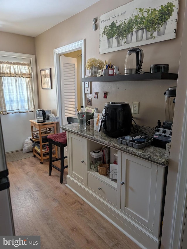 interior space featuring white cabinetry, dark stone countertops, and light hardwood / wood-style flooring