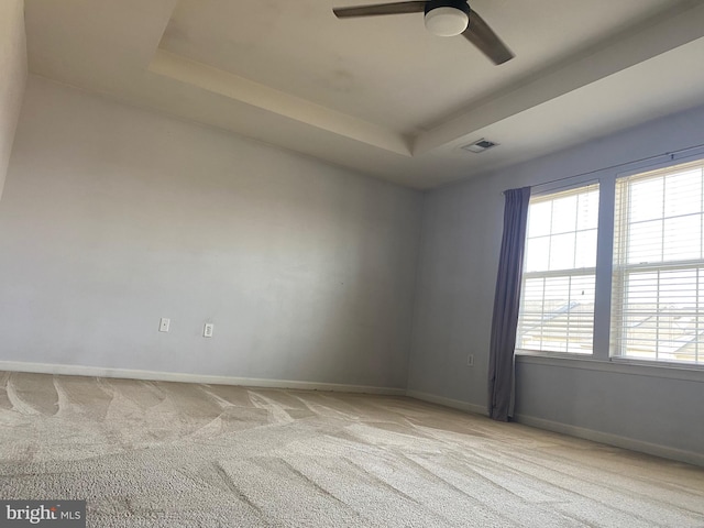 carpeted spare room with ceiling fan and a tray ceiling