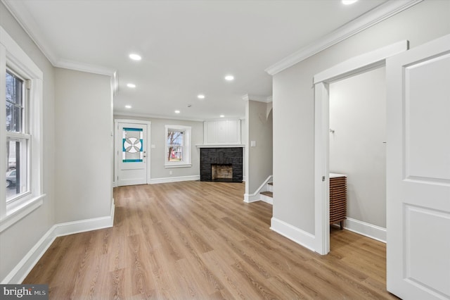 unfurnished living room featuring light hardwood / wood-style floors, ornamental molding, and a fireplace