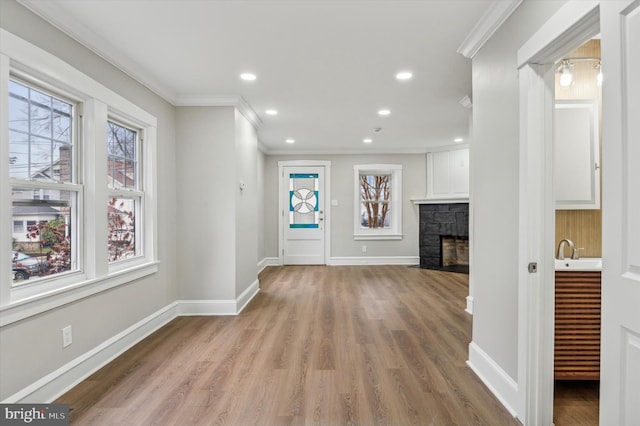 interior space featuring a fireplace, light hardwood / wood-style floors, sink, and crown molding