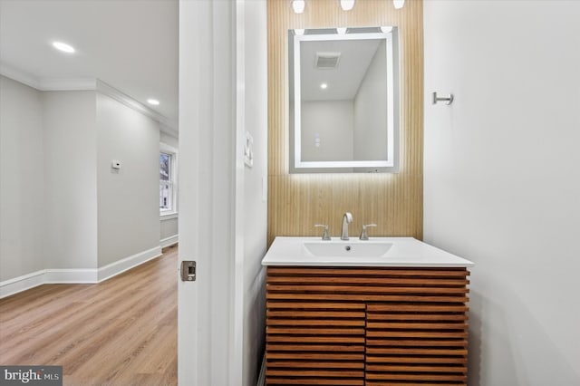 bathroom with hardwood / wood-style floors, vanity, and ornamental molding