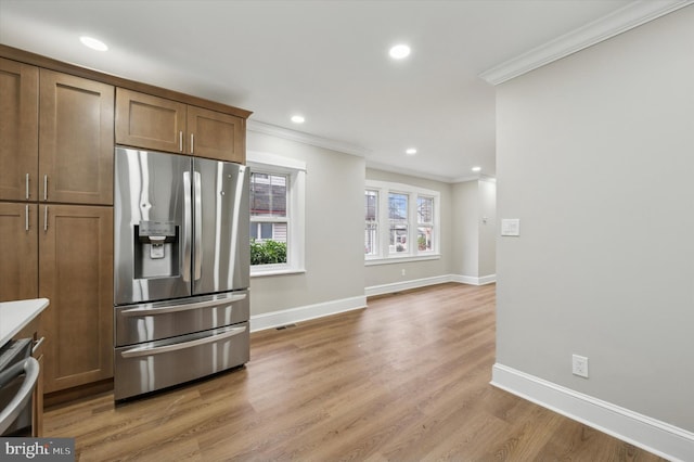 kitchen with ornamental molding, wood-type flooring, and appliances with stainless steel finishes