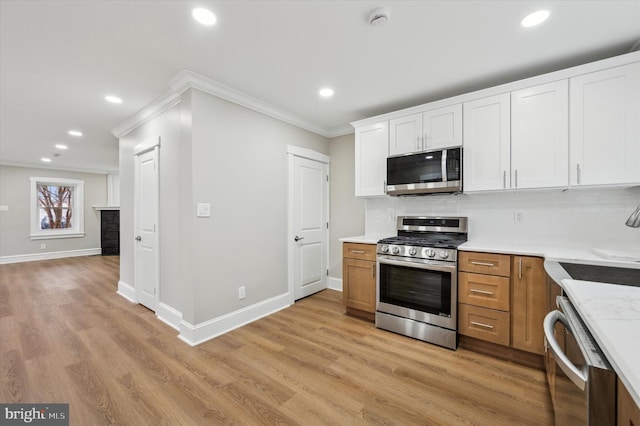 kitchen featuring appliances with stainless steel finishes, backsplash, ornamental molding, light hardwood / wood-style flooring, and white cabinets