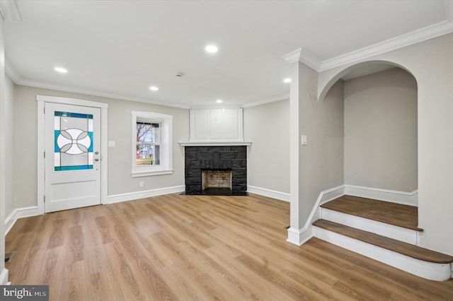 unfurnished living room featuring a stone fireplace, ornamental molding, and light hardwood / wood-style flooring