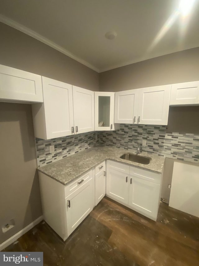 kitchen featuring white cabinets, light stone counters, and sink