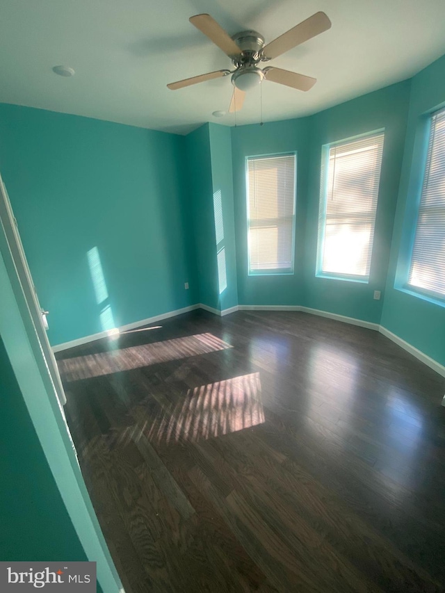 spare room featuring dark hardwood / wood-style floors, ceiling fan, and a wealth of natural light