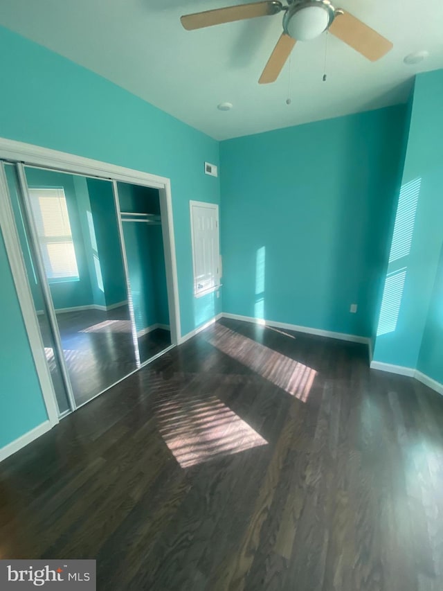 unfurnished bedroom featuring a closet, ceiling fan, and dark hardwood / wood-style flooring