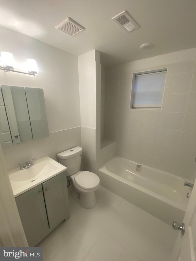 full bathroom with tiled shower / bath, tile walls, toilet, vanity, and tile patterned floors