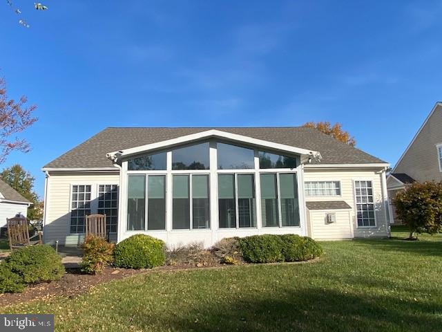 rear view of house with a sunroom and a yard