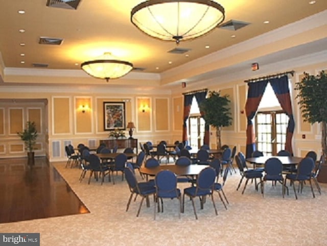 dining area with a tray ceiling, hardwood / wood-style flooring, and crown molding