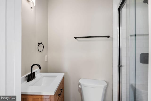 bathroom featuring vanity, walk in shower, and toilet