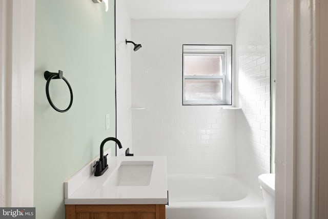 full bathroom featuring vanity, tiled shower / bath combo, and toilet