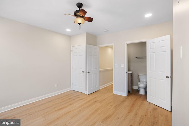 unfurnished bedroom featuring a closet, light hardwood / wood-style floors, ensuite bath, and ceiling fan