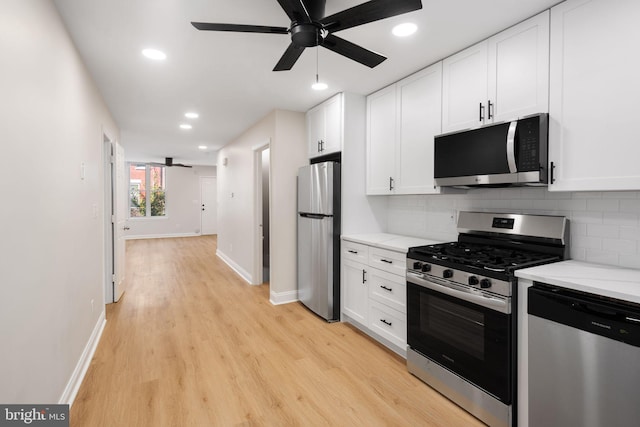 kitchen with appliances with stainless steel finishes, backsplash, ceiling fan, white cabinets, and light hardwood / wood-style flooring