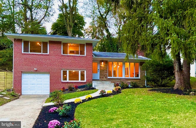 tri-level home featuring a garage and a front lawn