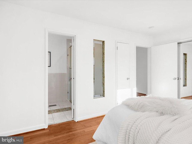 bedroom with ensuite bathroom and hardwood / wood-style floors