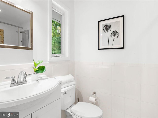 bathroom featuring vanity, toilet, and tile walls