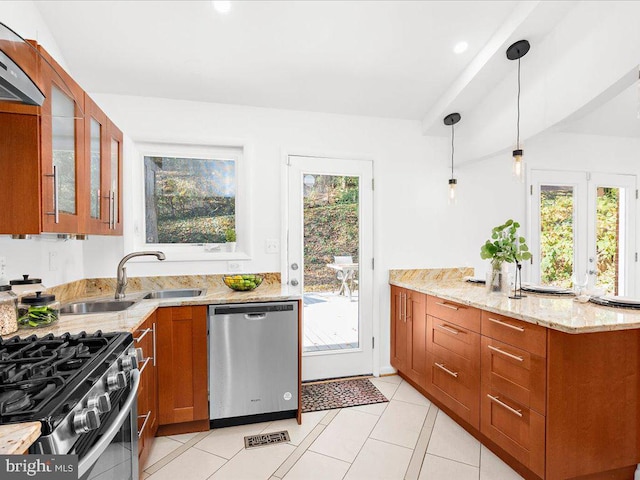 kitchen with light stone counters, pendant lighting, light tile patterned floors, exhaust hood, and appliances with stainless steel finishes