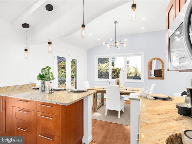 kitchen featuring french doors, light stone counters, vaulted ceiling, decorative light fixtures, and light hardwood / wood-style flooring