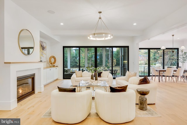 living room featuring a wealth of natural light, an inviting chandelier, and light hardwood / wood-style floors