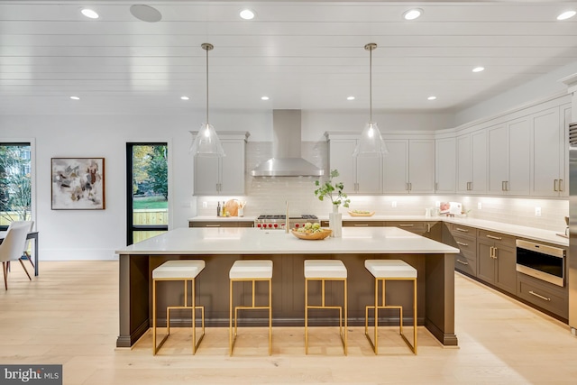 kitchen with wall chimney exhaust hood, hanging light fixtures, and a wealth of natural light