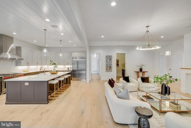 living room featuring an inviting chandelier, sink, and light wood-type flooring