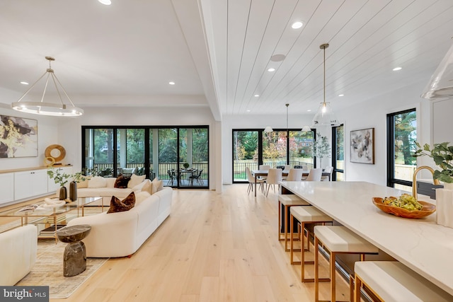 living room featuring a chandelier, light hardwood / wood-style flooring, and wooden ceiling