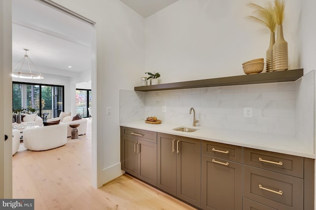 kitchen with sink, decorative backsplash, decorative light fixtures, and light wood-type flooring