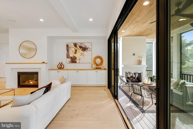 living room featuring beam ceiling, light hardwood / wood-style floors, and plenty of natural light