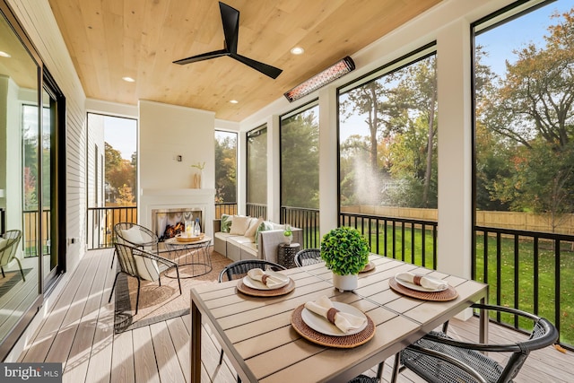 sunroom / solarium with a multi sided fireplace, wooden ceiling, and ceiling fan