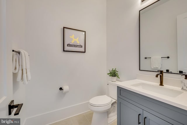 bathroom with toilet, vanity, and tile patterned flooring