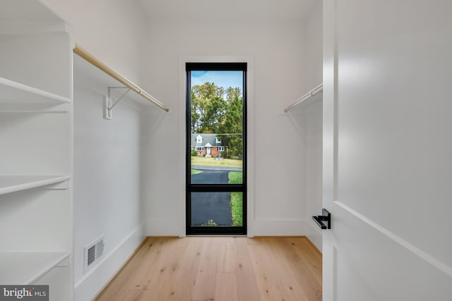 walk in closet with light hardwood / wood-style floors