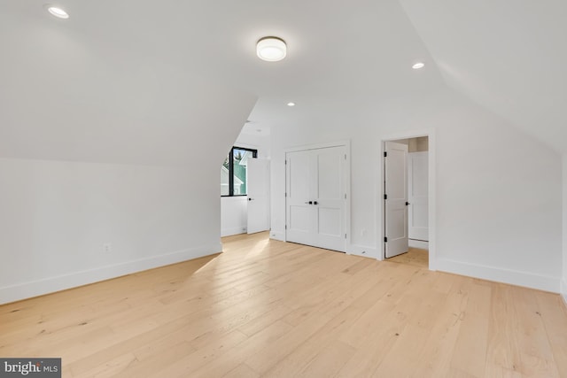 additional living space featuring vaulted ceiling and light wood-type flooring