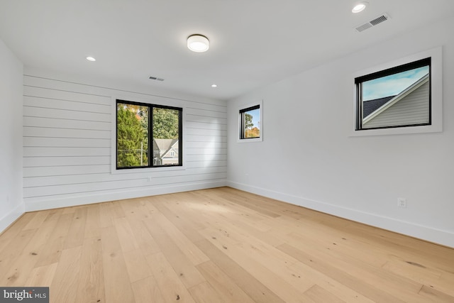 unfurnished room featuring wood walls and light wood-type flooring