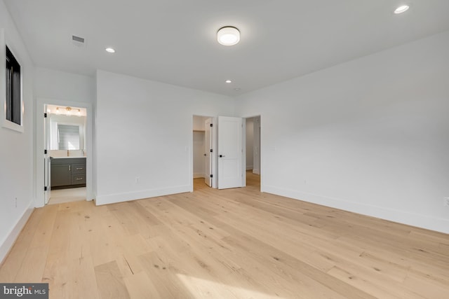 unfurnished bedroom featuring ensuite bathroom and light wood-type flooring