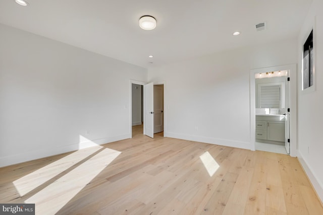 unfurnished bedroom featuring ensuite bath and light hardwood / wood-style flooring